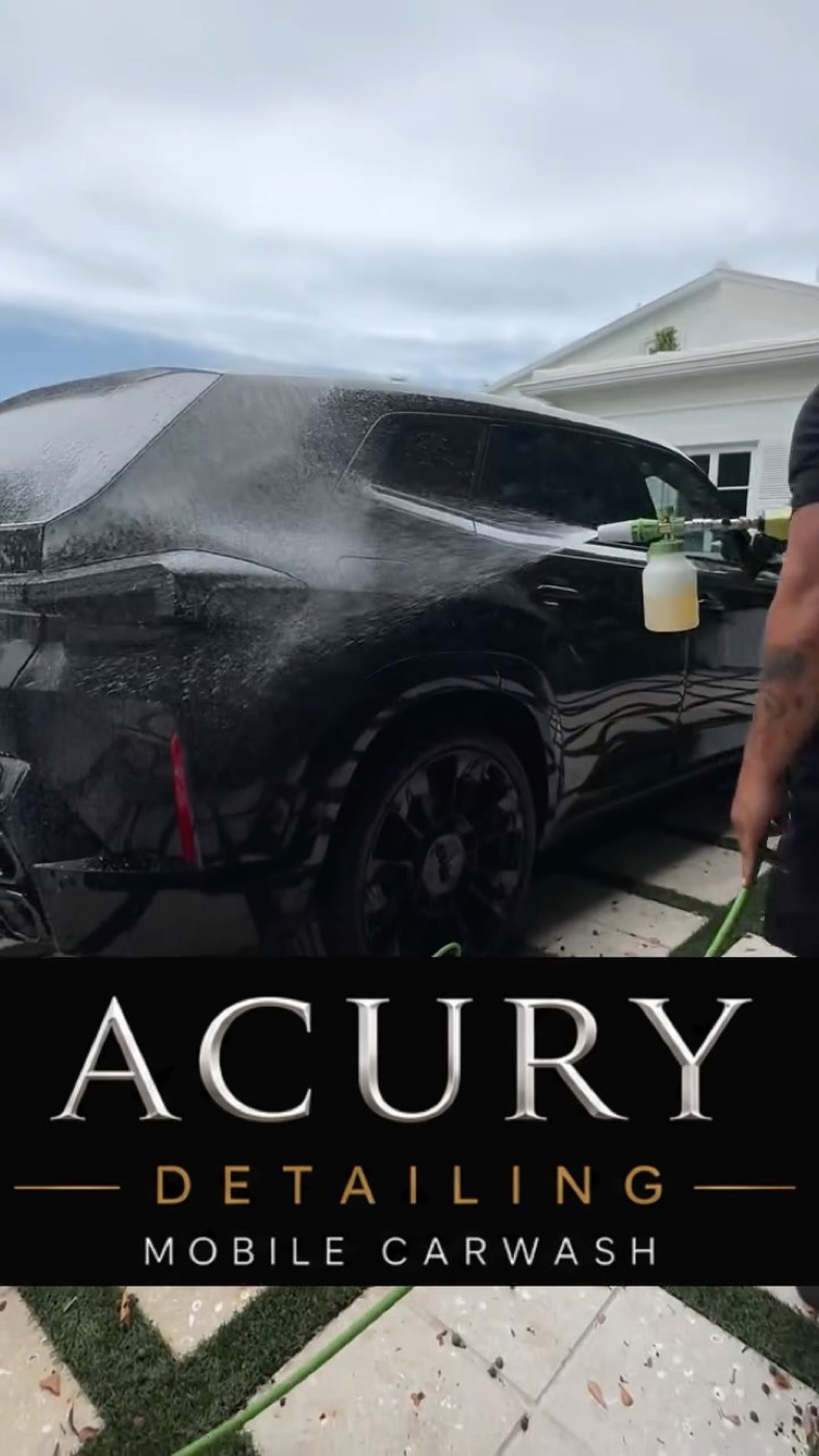 Acury Detailing washing a black BMW XM in a client's driveway